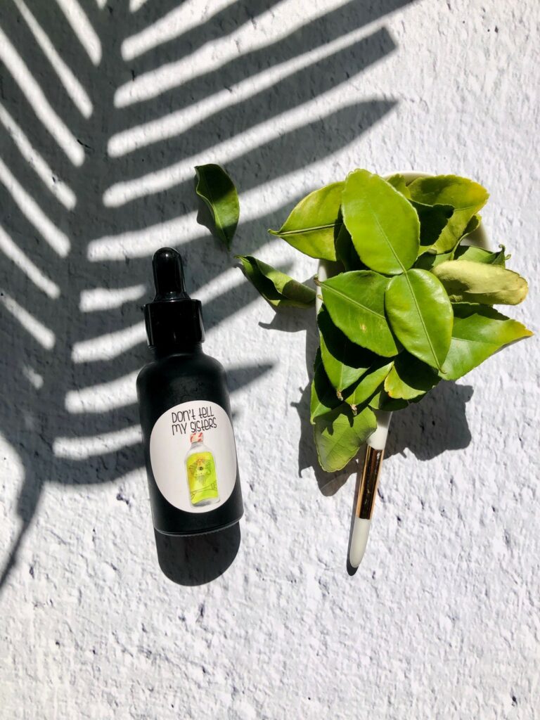 Picture of a black bottle with a sticker on it and tropical plant leaf shadow