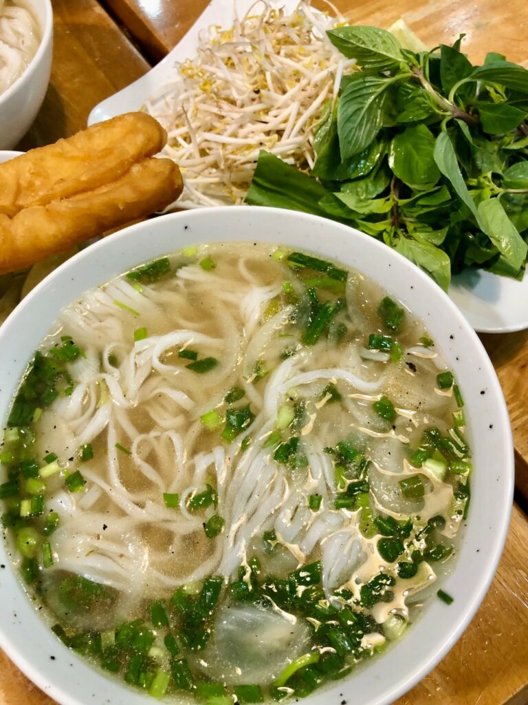 Picture of the best Pho in Saigon with herbal leaves, soy beans and you tiao